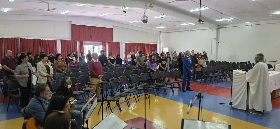 Asistentes de pie durante la Misa Comunitaria en el Salón de Actos